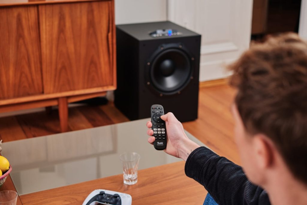 ULTIMA 20 CONCEPT Surround Power Edition "5.1-Set" Una persona maneja el sistema ULTIMA 20 CONCEPT Surround Power Edition con un mando a distancia